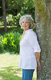 Portrait of a mature woman leaning against tree trunk