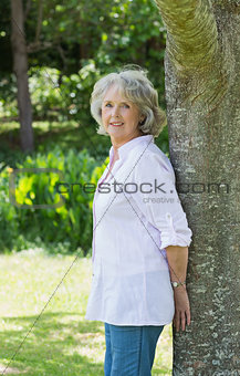 Portrait of a mature woman leaning against tree trunk