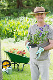 Smiling man holding potted plant in garden