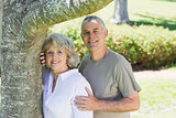 Smiling mature couple besides tree at park