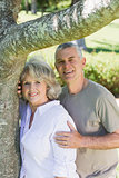 Smiling mature couple besides tree at park