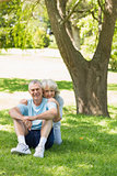 Smiling mature couple sitting on grass at park