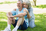 Smiling mature couple sitting on grass at park