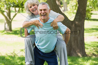 Cheerful mature man carrying woman at park