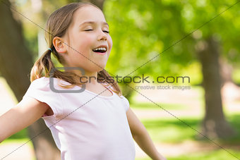 Girl with arms outstretched and eyes closed at park