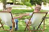 Relaxed mature couple sitting in deck chairs at park