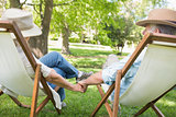 Mature couple sitting in deck chairs at park