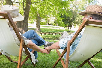 Mature couple sitting in deck chairs at park