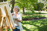Smiling mature woman painting in park
