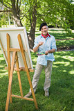 Mature man painting on canvas in park