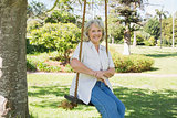 Smiling mature woman sitting on swing in park