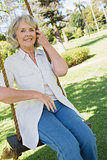 Smiling mature woman sitting on swing in park