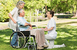 Women with mature man sitting in wheel chair at park
