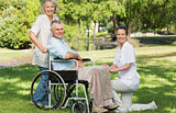 Women with mature man sitting in wheel chair at park