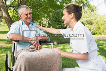 Woman with mature father sitting in wheel chair at park