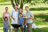 Extended family standing at barbecue in park