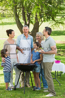 Extended family standing at barbecue in park