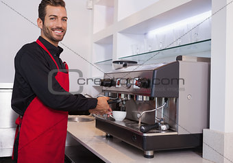 Smiling young barista making cup of coffee