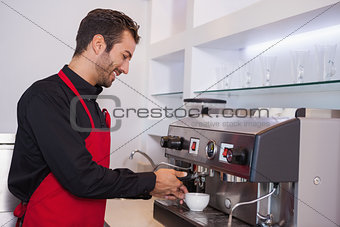 Happy attractive barista making cup of coffee