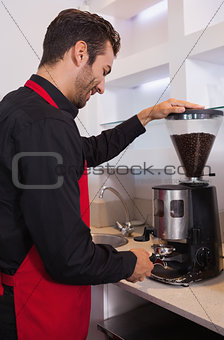 Happy barista grinding coffee beans