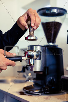 Barista pressing down fresh coffee grounds