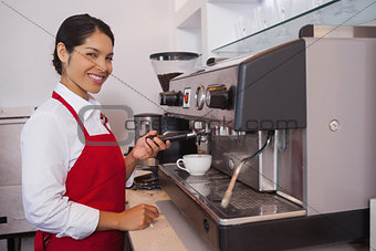 Pretty barista making coffee smiling at camera