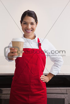 Pretty young barista offering cup of coffee to go