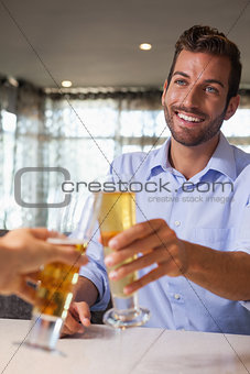 Happy businessman clinking glass of beer with bartender