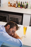 Drunk businessman sleeping beside glass of beer