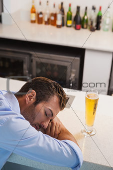 Drunk businessman sleeping beside glass of beer