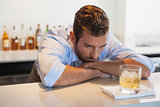 Drunk businessman looking at his whiskey glass after work
