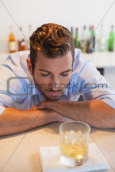 Drunk businessman looking at his whiskey glass