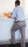 Businessman standing at the bar holding glass of whiskey