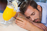 Drunk businessman sleeping on bar beside cocktail