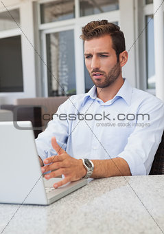 Stressed businessman working on laptop at table