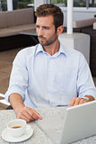 Focused businessman working with laptop at table