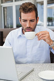 Handsome businessman working with laptop drinking coffee