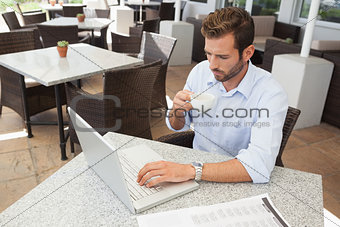 Frowning young businessman working at laptop