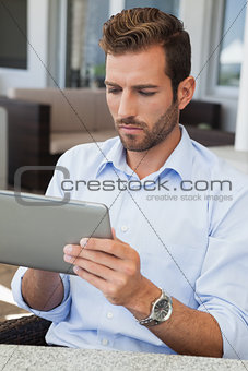 Serious young businessman working on tablet