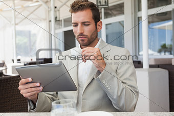 Handsome young businessman working on tablet drinking espresso