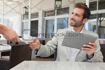 Cheerful businessman working with digital tablet taking his espresso