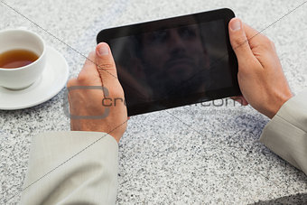 Businessman holding small tablet at table