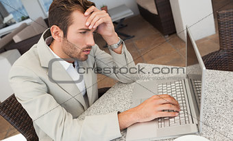 Stressed businessman working with his laptop at table