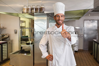 Smiling young chef looking at camera showing thumb up