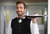 Smiling waiter holding tray with plate of dessert