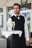Handsome waiter holding tray of champagne