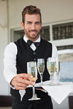 Handsome waiter offering flute of champagne