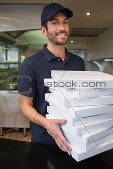 Happy pizza delivery man holding many pizza boxes