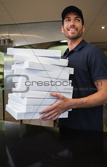 Cheerful pizza delivery man holding many pizza boxes