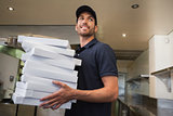 Smiling pizza delivery man holding many pizza boxes